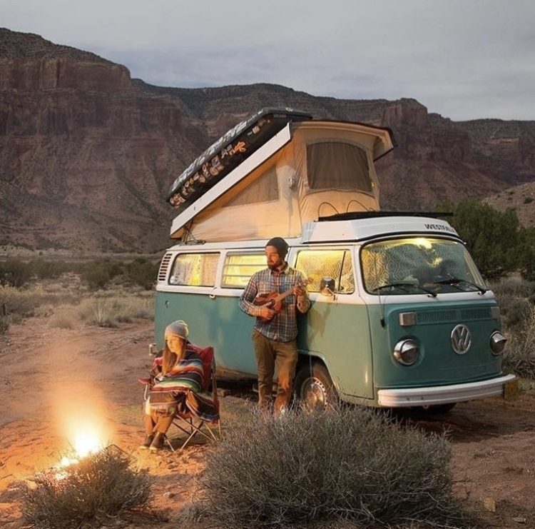 Campfire outside a blue VW bus.