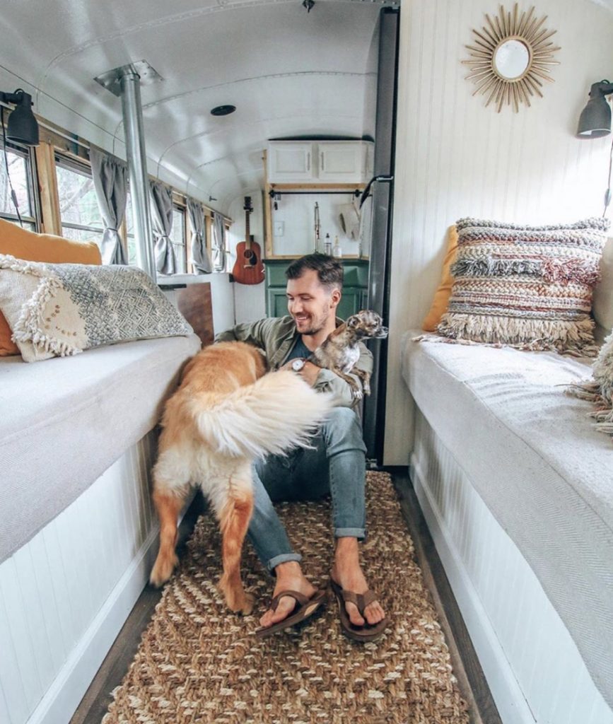 Man in converted bus with two dogs.