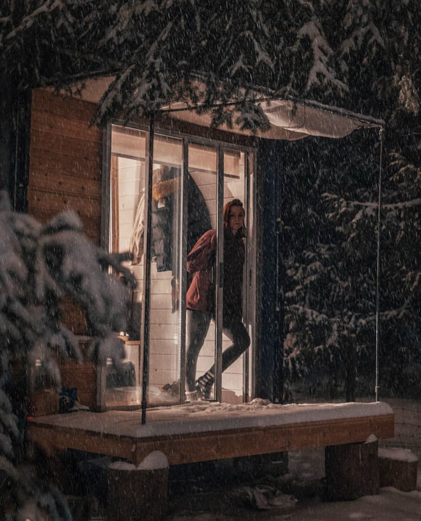 Shipping container home lit up in snow at night.