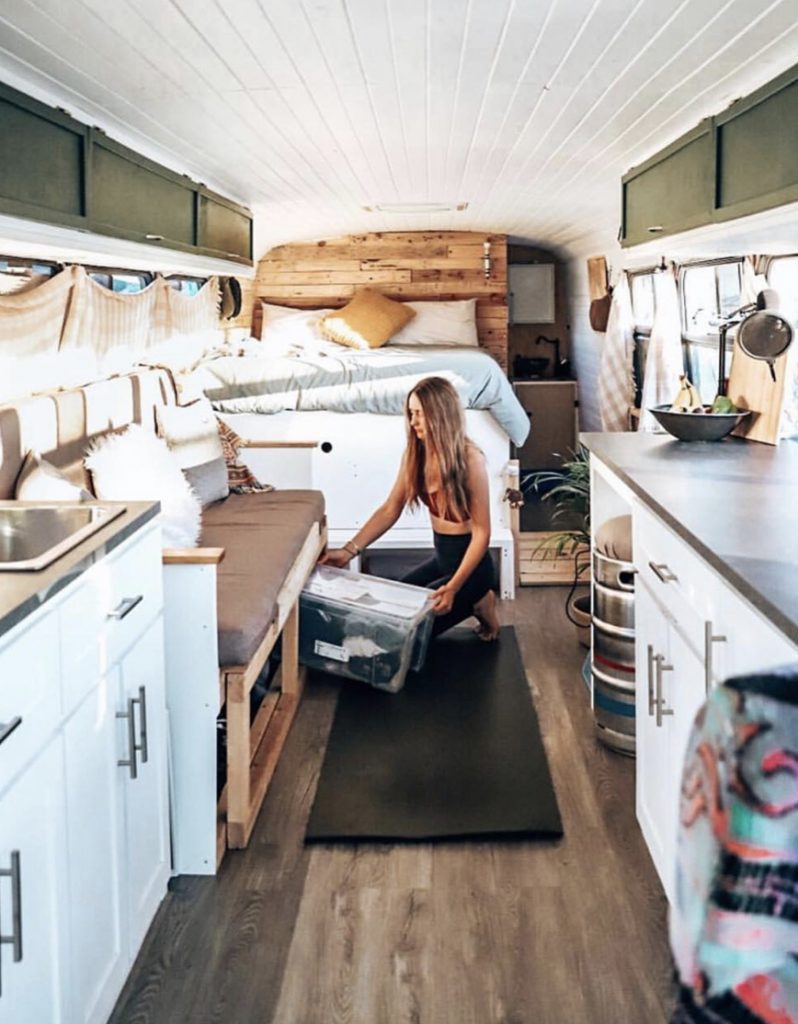 Woman tidying away in her bus conversion.