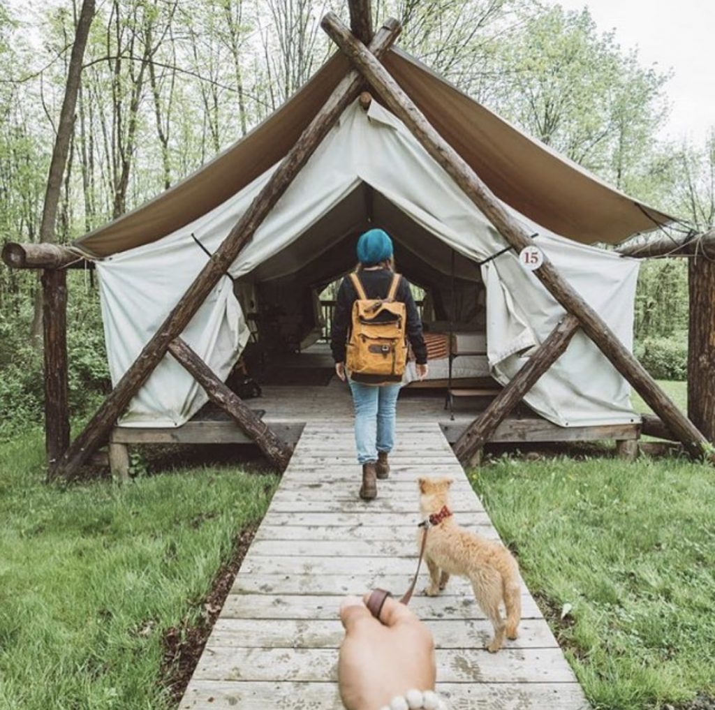 Woman and dog walking into tewnt home. Tiny house youtube.