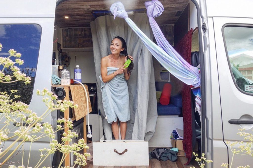 Woman showering in her sprinter van camper.