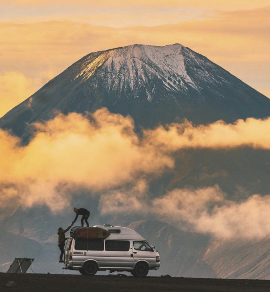 Van with surf rack in front of mountains.