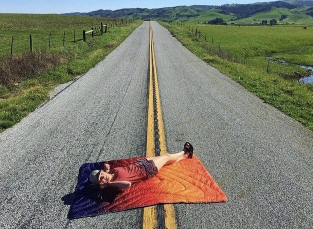 Man lying on rumpl on deserted road in the countryside.
