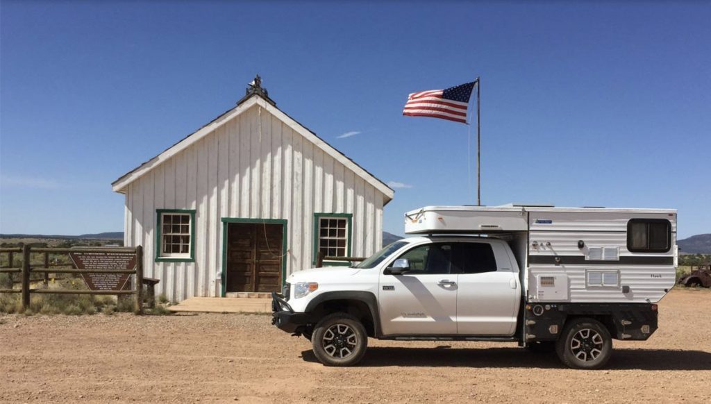 Four wheel camper outside barn with American flag 