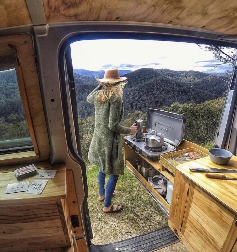 Woman cooking on slide out outdoor kitchen from her van.