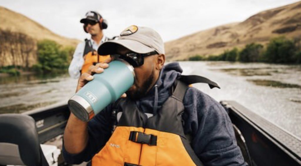 Best Camping Flasks - blue yeti rambler being used on a boat