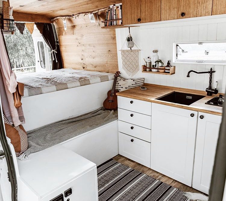 Custom van ideas - white interior with double bed at back with bench infront and kitchen to the side.
