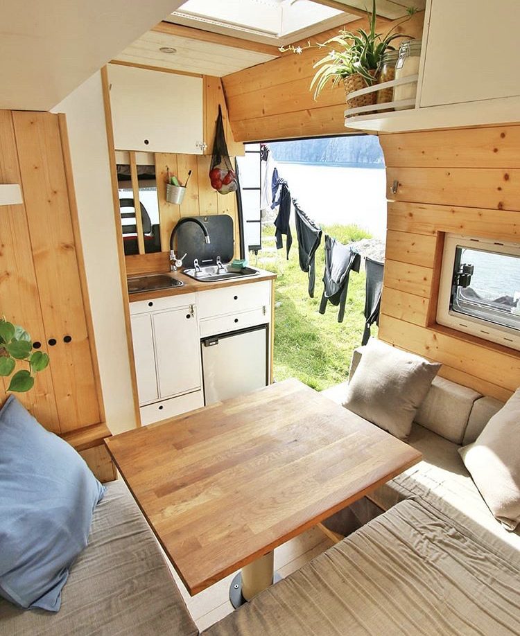 Wooden interior of van with U-shaped sofa and bulkhead kitchen