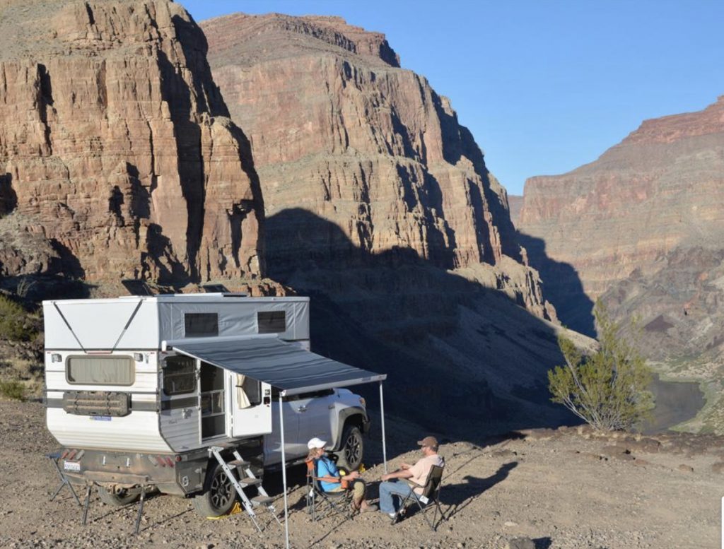 Hawk Truck camper exterior with roof popped and awning open infront of Rocky Mountains.