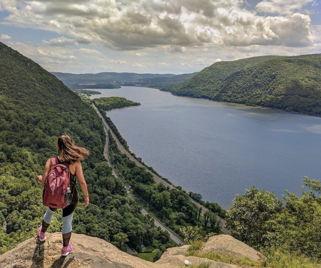 What to bring on a hike : woman overlooking lake and trees on hike
