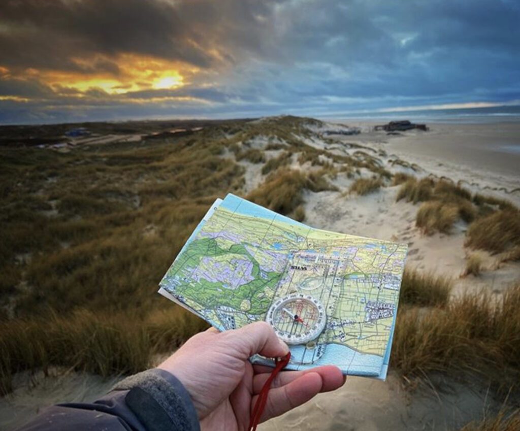 Map and compass held in hand in front of beach