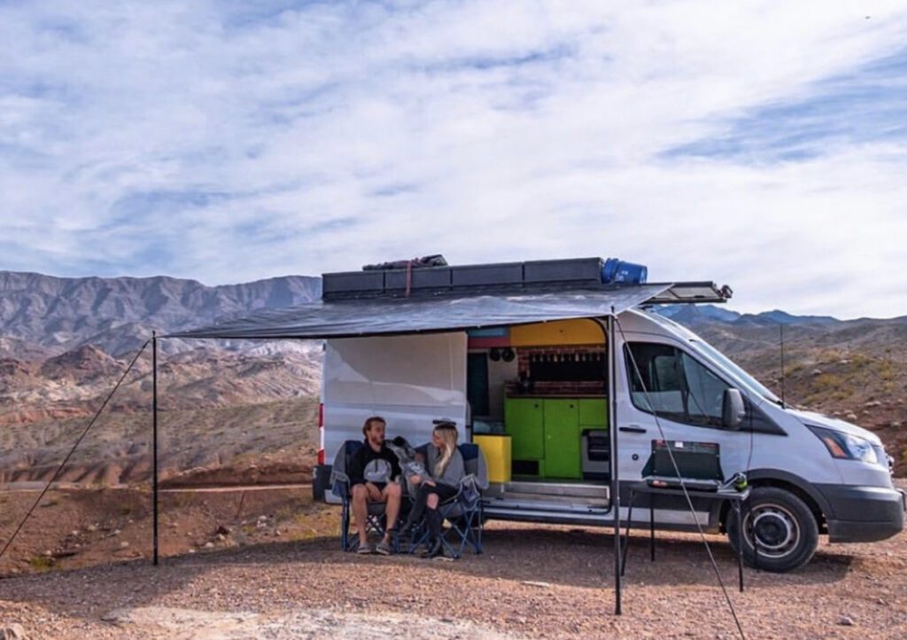 People sat outside van under an awning
