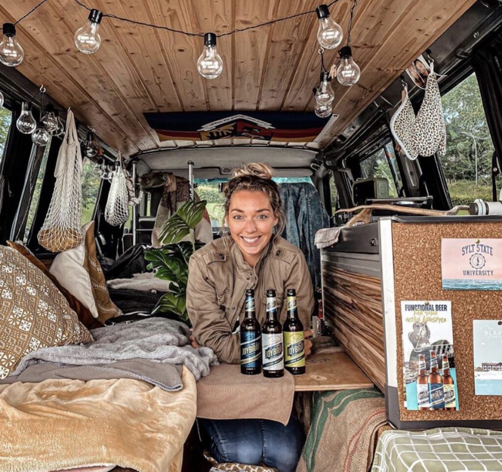 Small RV - woman sat at multi-functional bed/seat/table inside van
